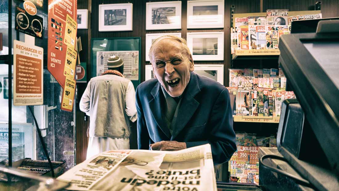 old man laughing at news stand