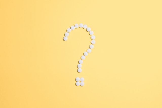 question mark made of pills on yellow background