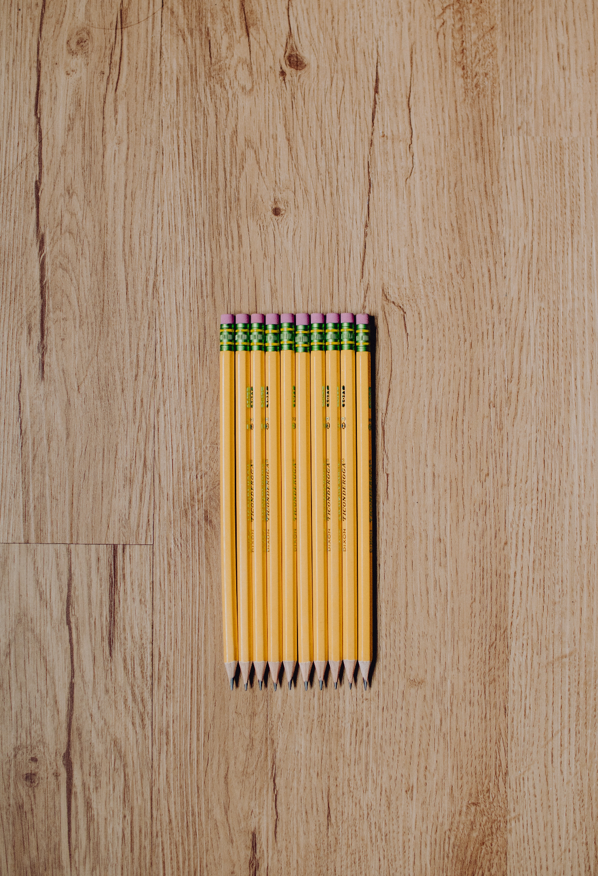 ten neatly lined up number 2 pencils on a wood surface.