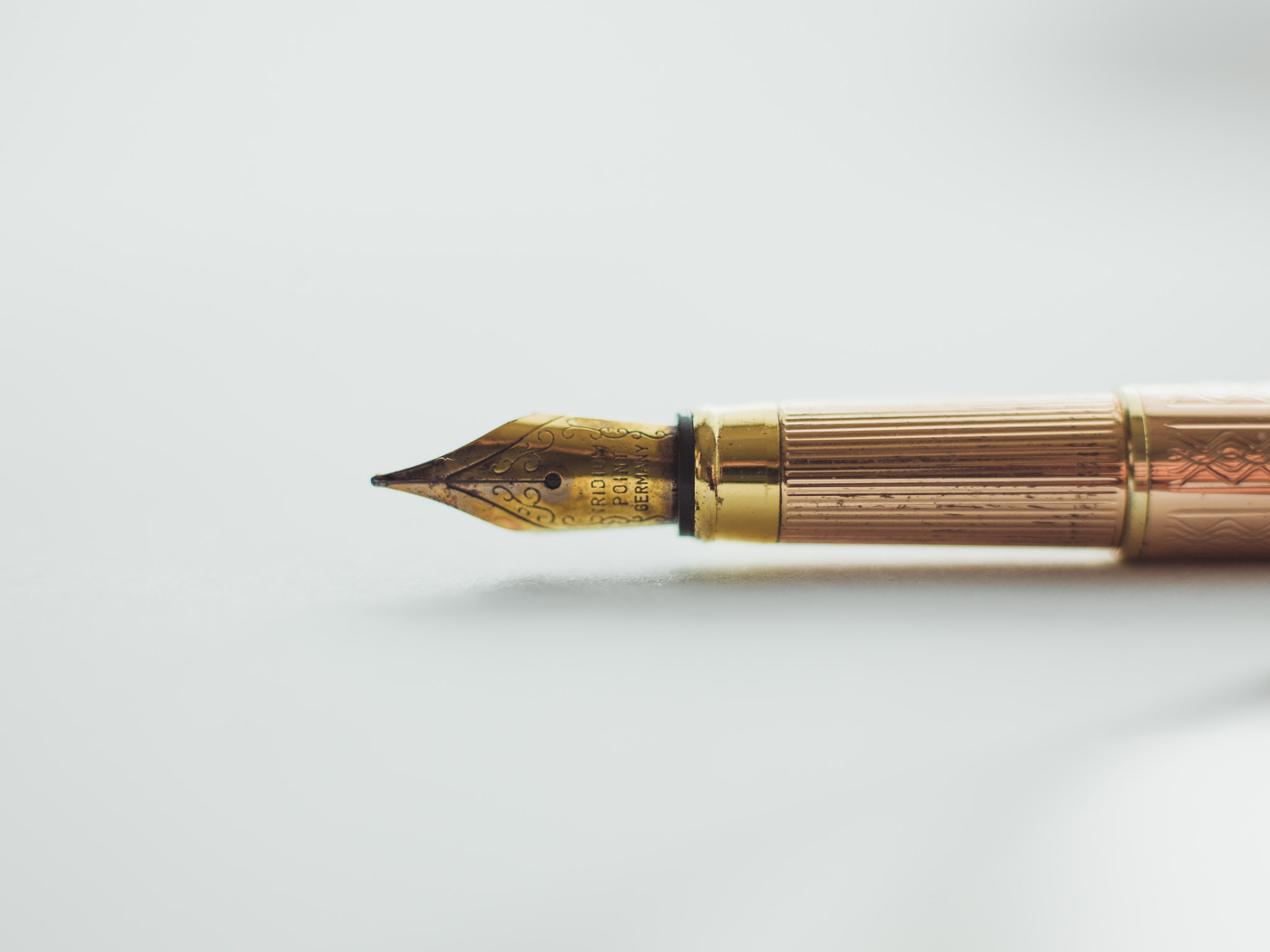 A fountain pen with a gold nib laying on its side
