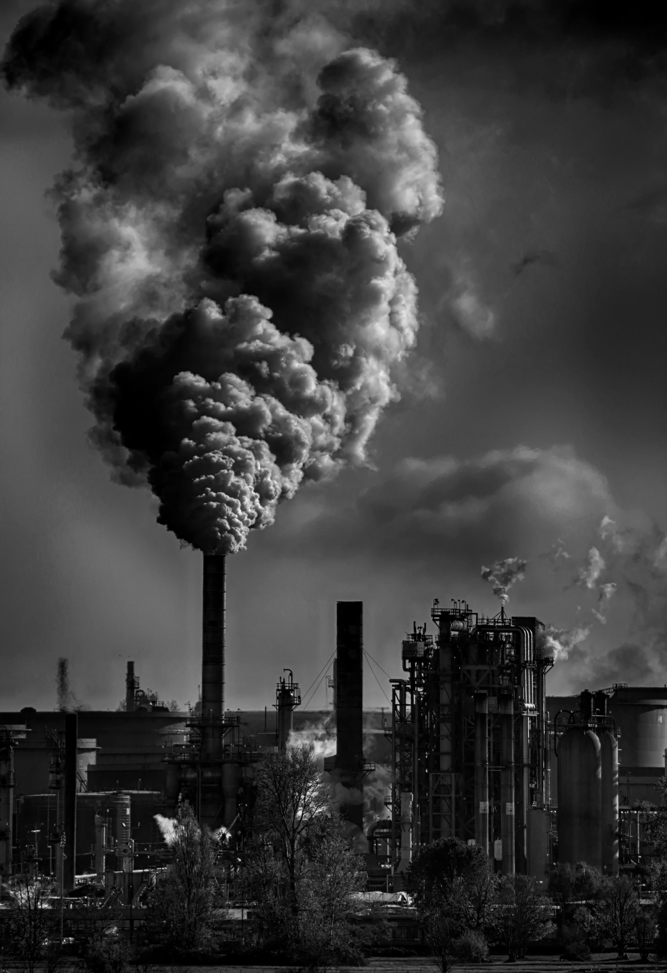 A factory belching out plumes of grey smoke.
