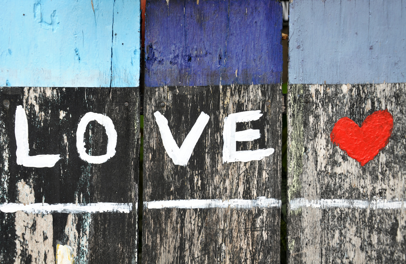 a fence with the word love and a red heart painted on it.