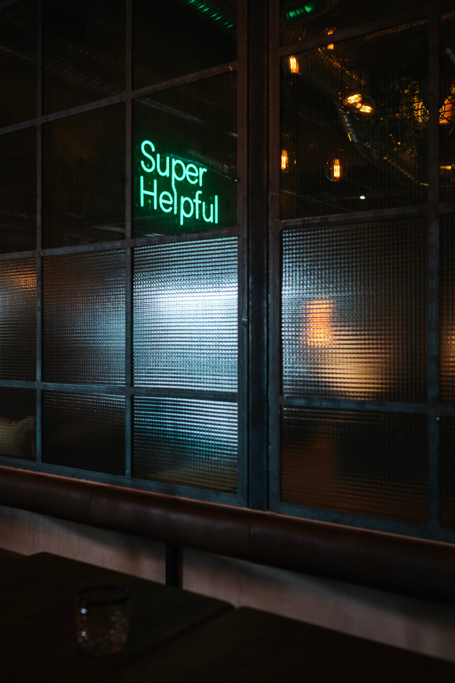 Outside a shop looking in and a green neon sign reading super helpful