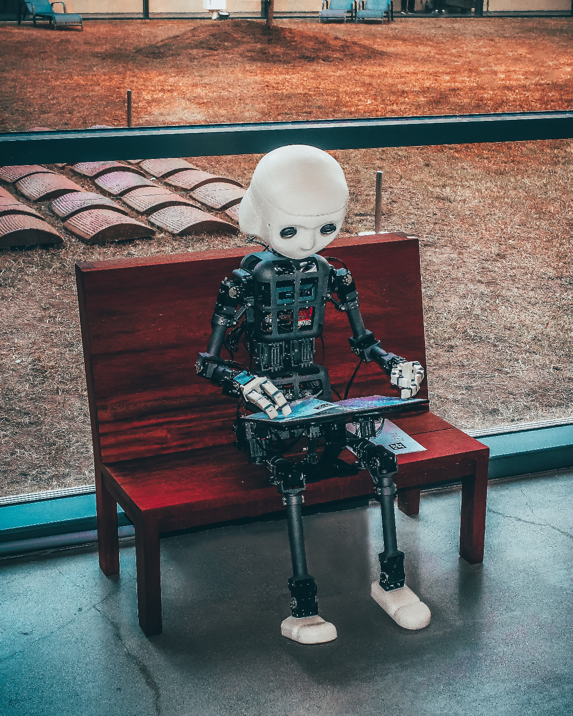a robot sitting on abench working a laptop