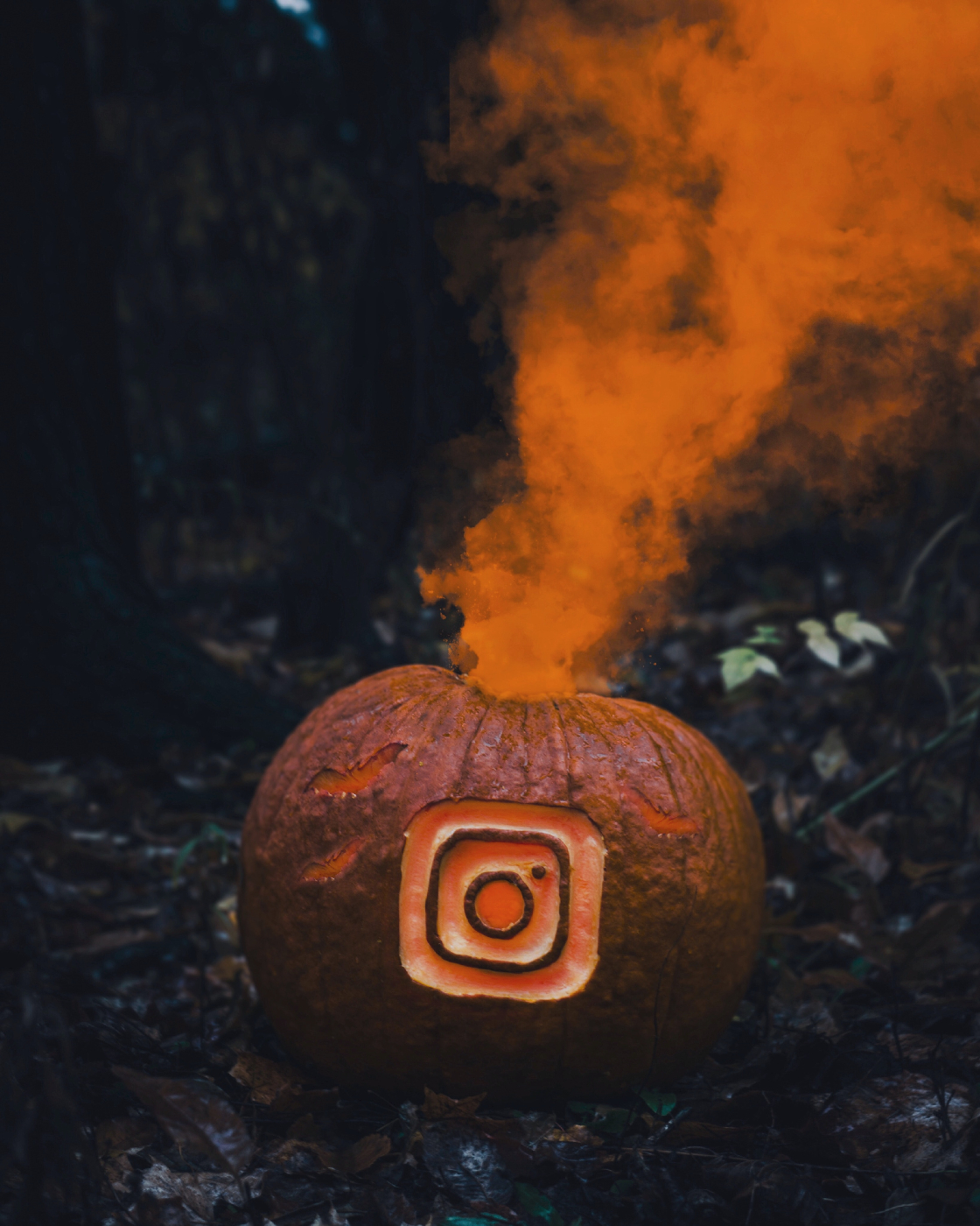 A pumpkin with the Instagram icon carved in it and orange smoke coming out 