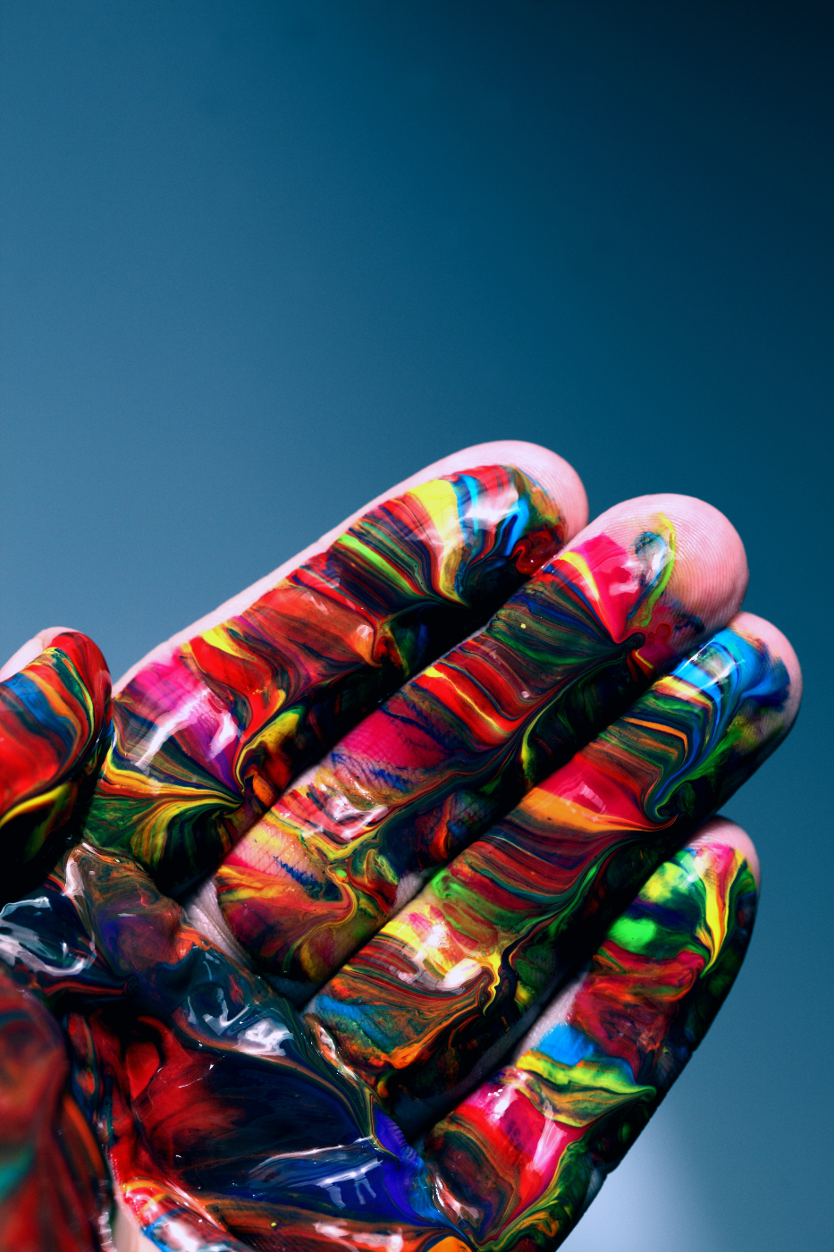 a hand covered in multi colored paint
