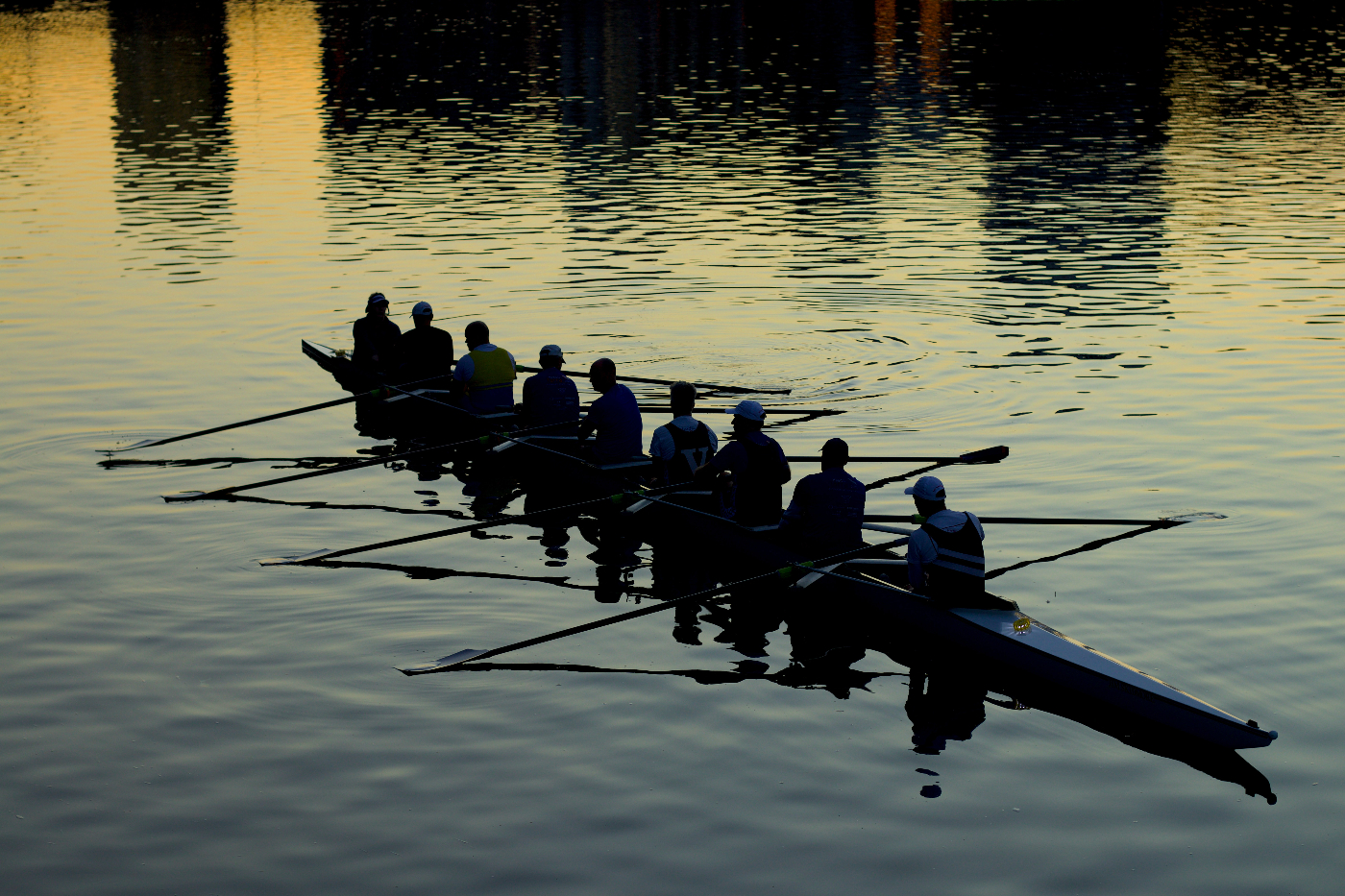 Nine men in a rowing shell at sunset