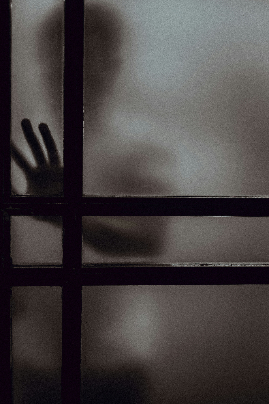 A person behind translucent glass touching the glass
