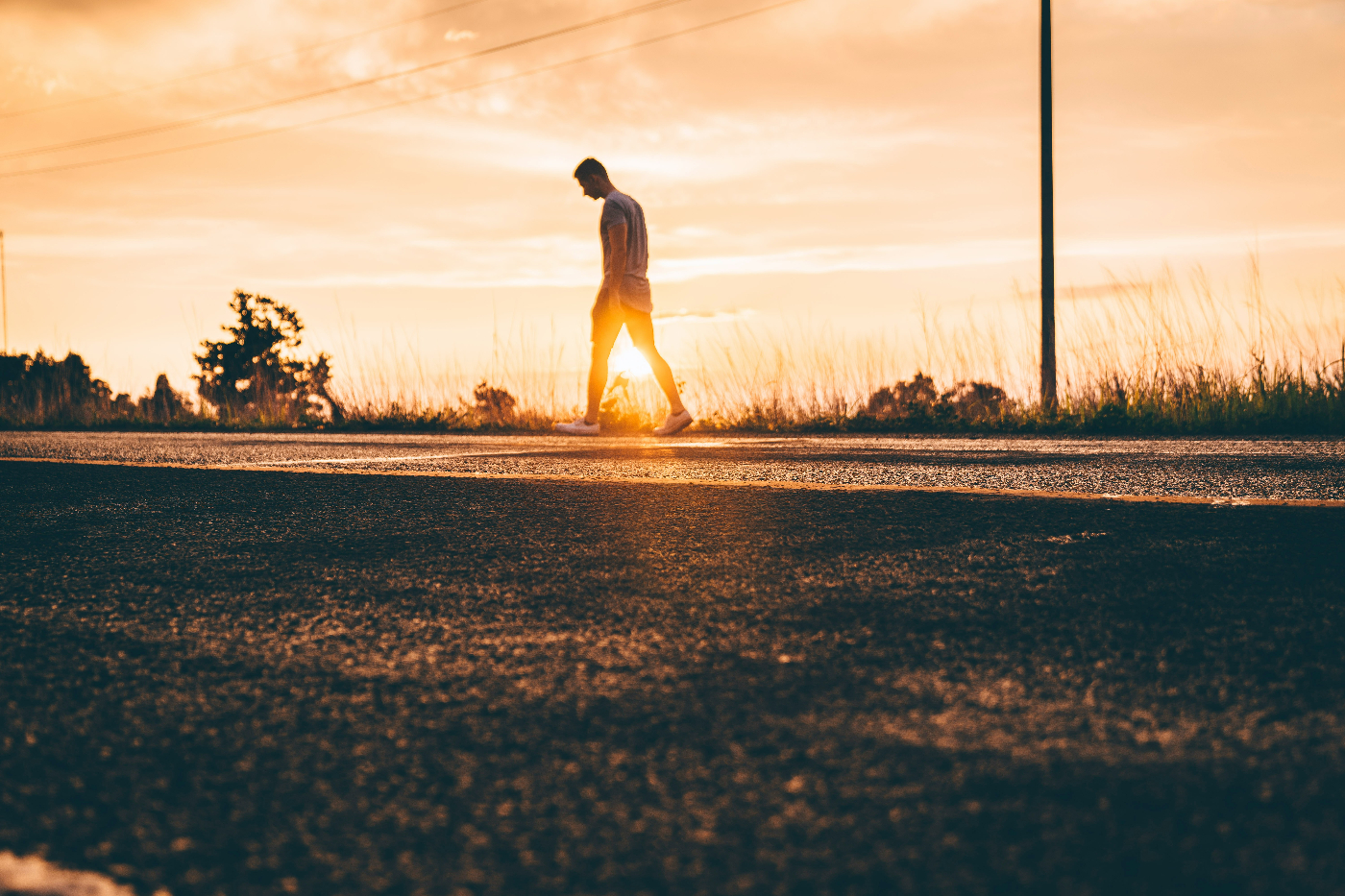 Sunset a man walking alone by the side of a highway