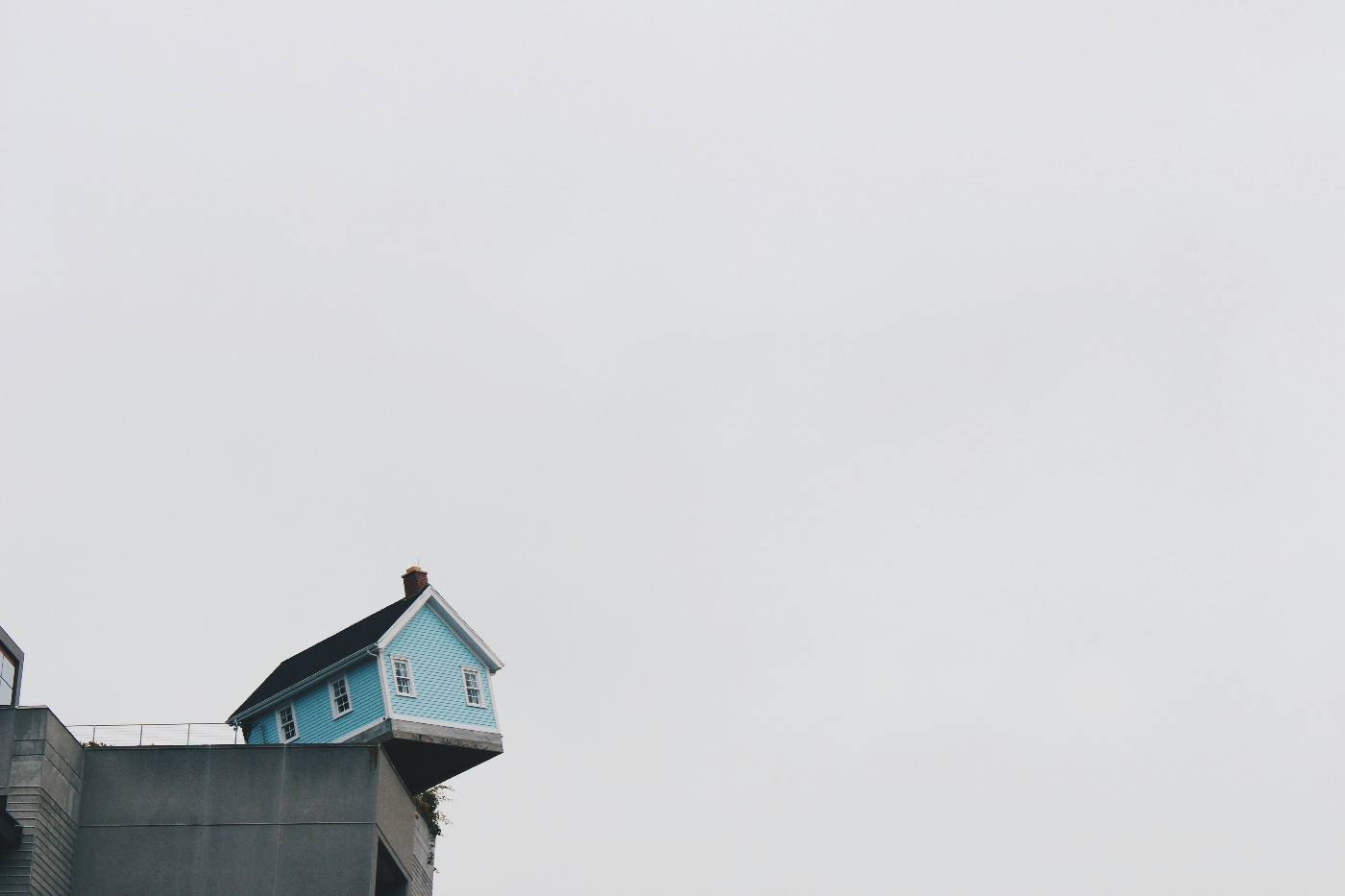 A small blue house hanging off the side of a cliff