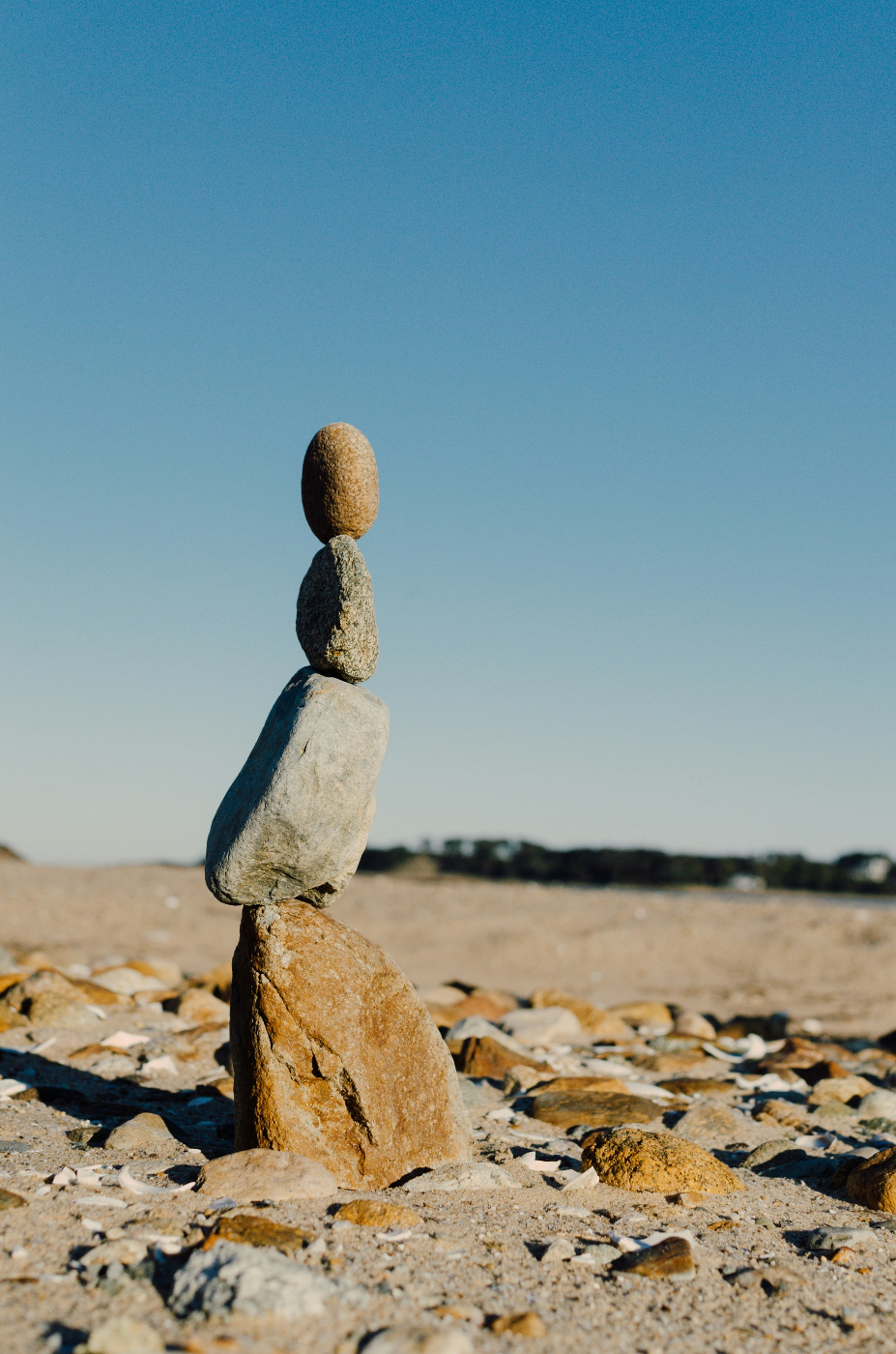 4 very different rocks balanced in a tower on a beach