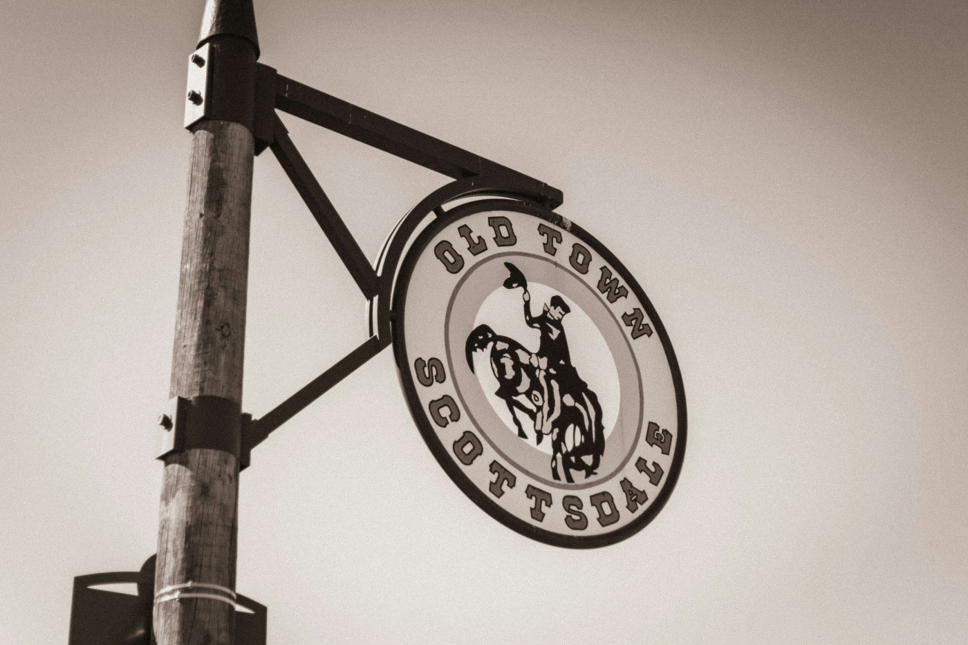 An old, round sign with a cowboy riding a bucking bronco reading Old Town Scottsdale