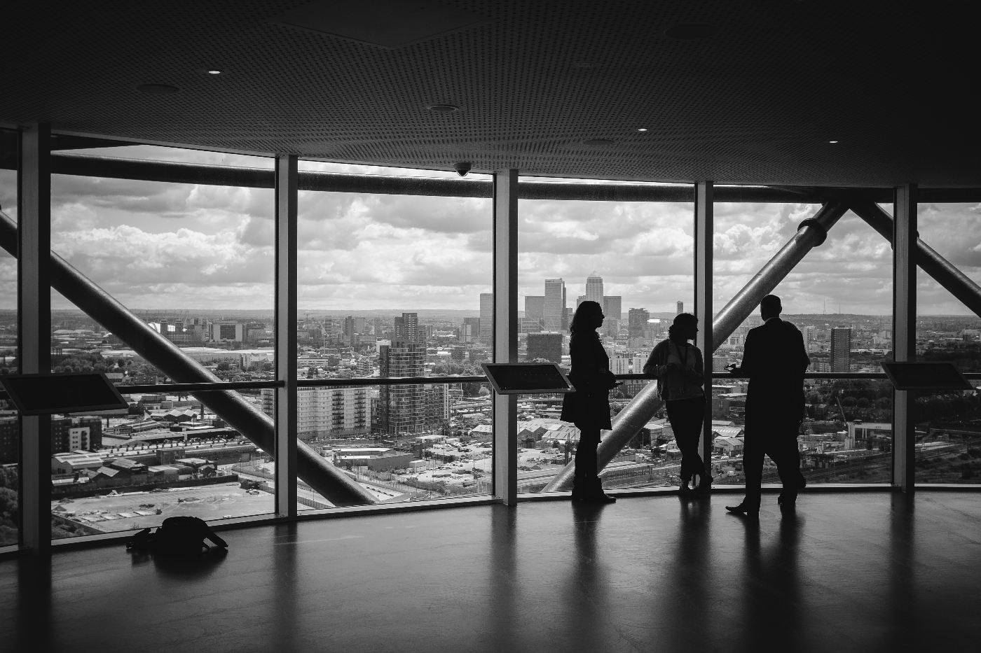 Black and white image of three people checking out the view in a new, empty office space