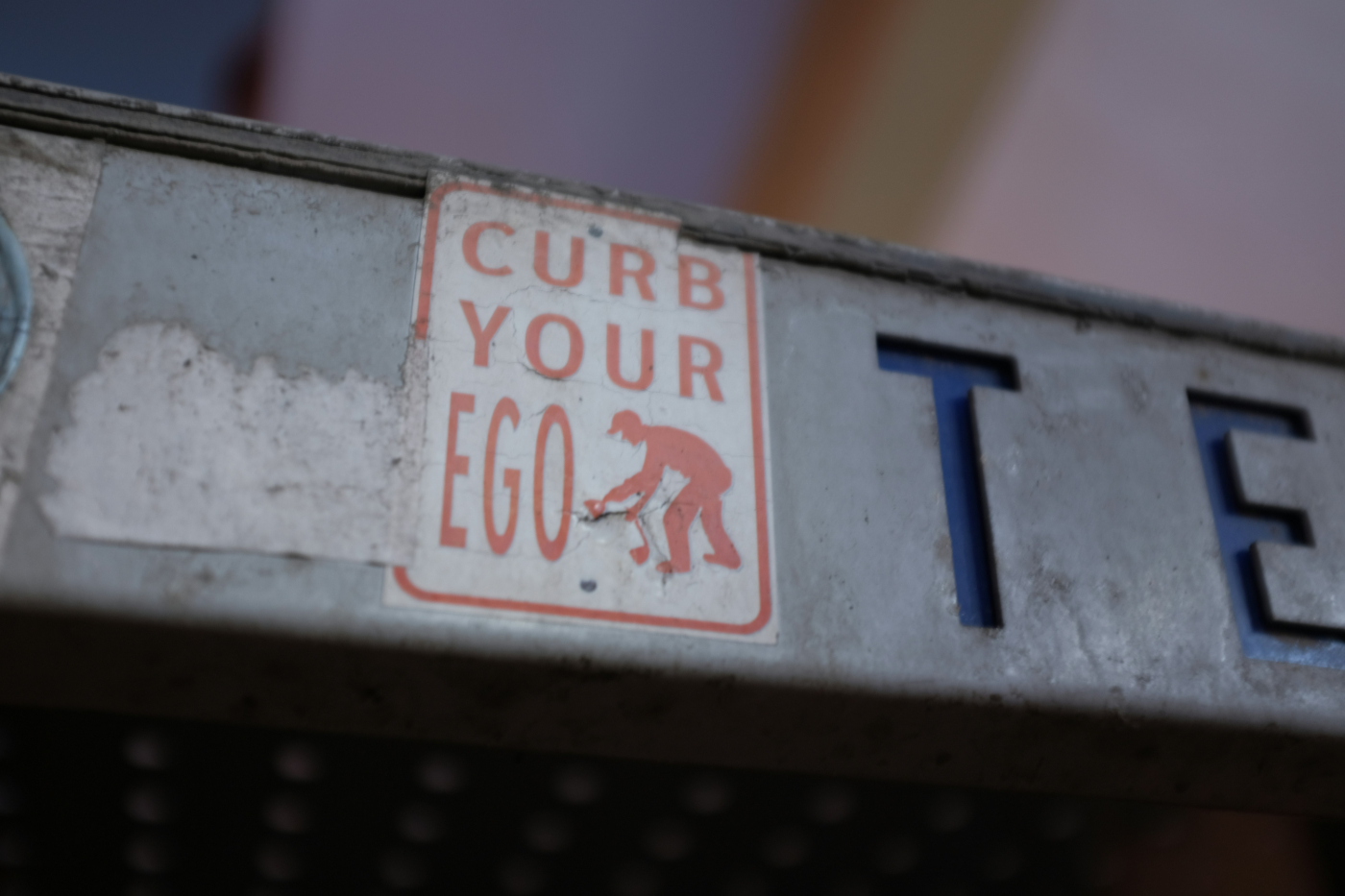 A small red sign with the image of person and the words Curb Your Ego