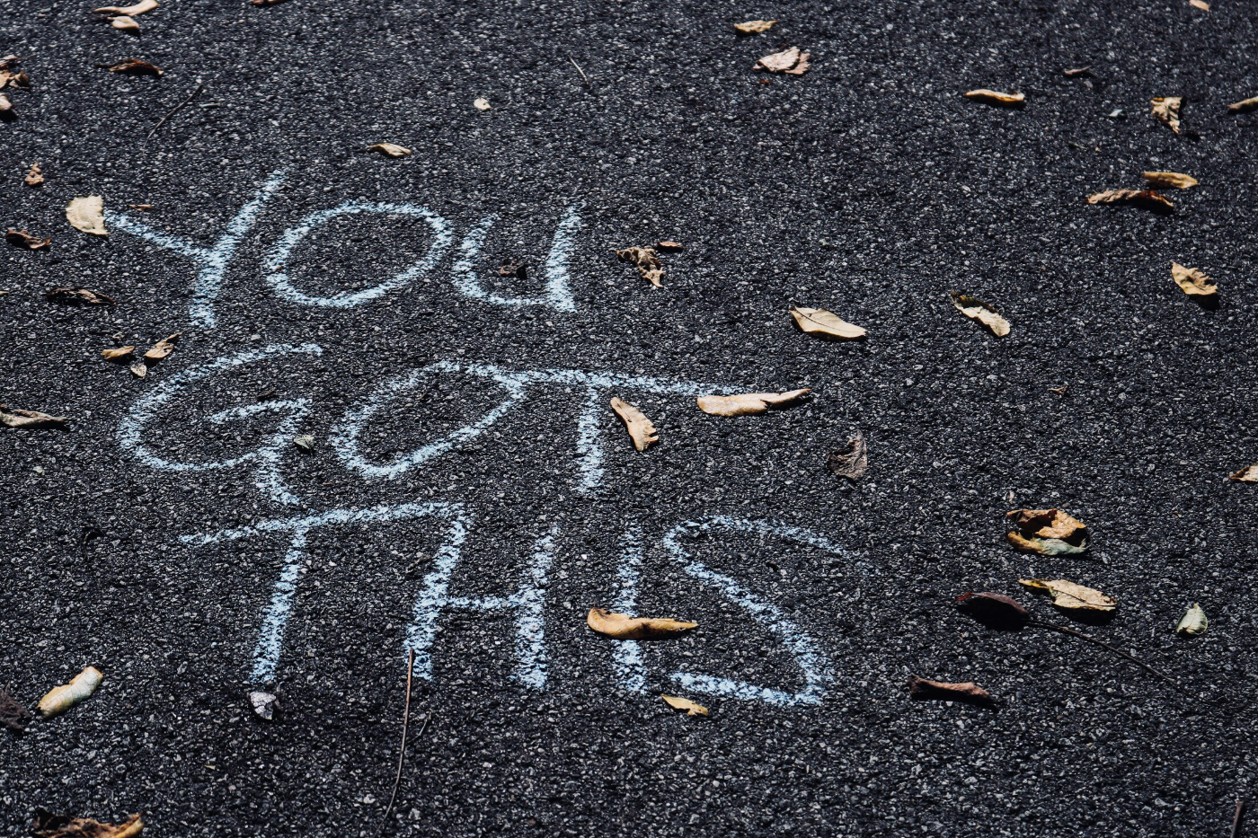 A black street someone has written on with white chalk reading You Got This