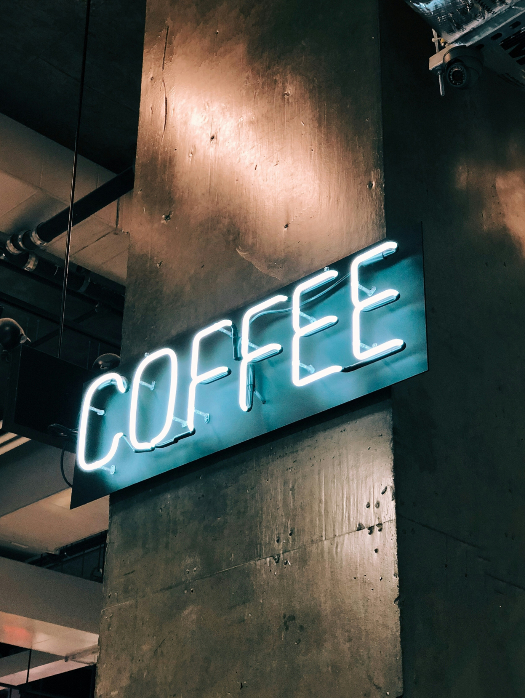 A blue neon sign on a wood support reading COFFEE