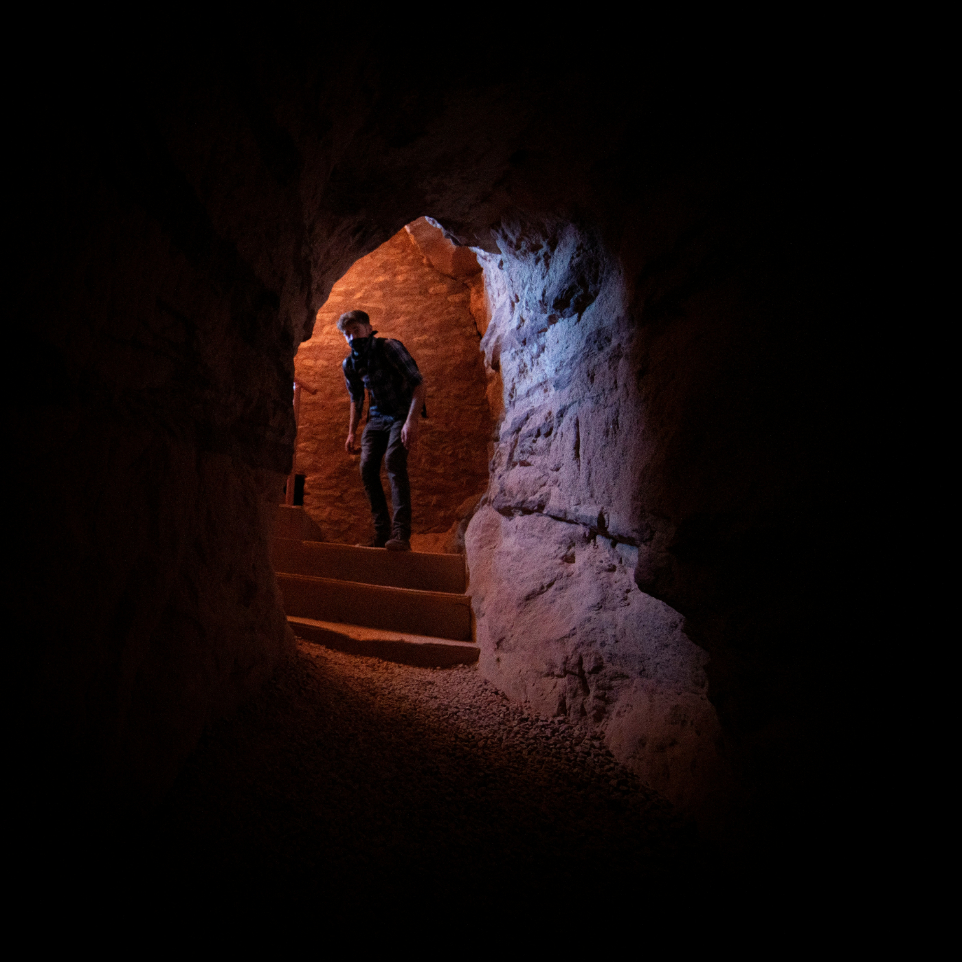 A man standing on stairs at the opening of a cave