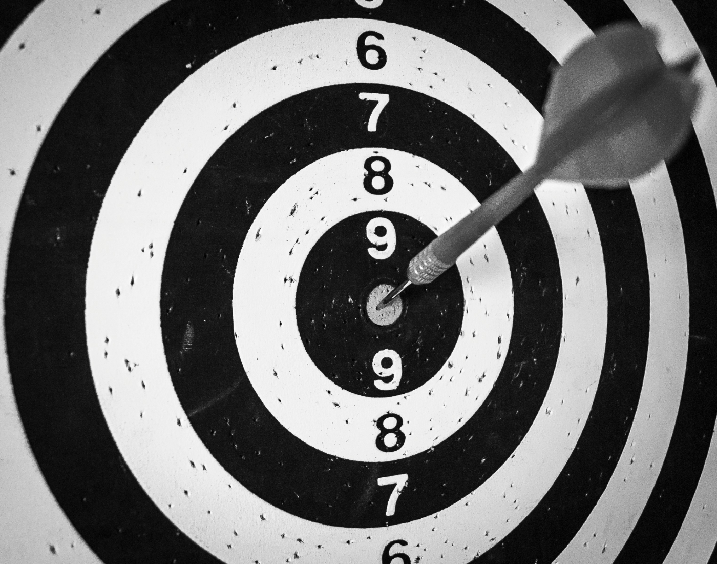 A black and white dart board with a dart in the bull's eye