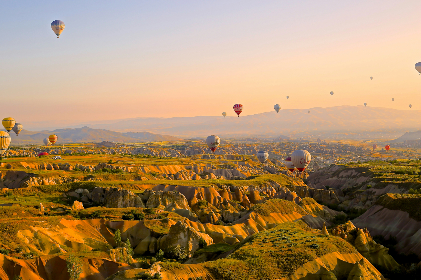 Hundreds of hot air balloons rising over a high desert landscape
