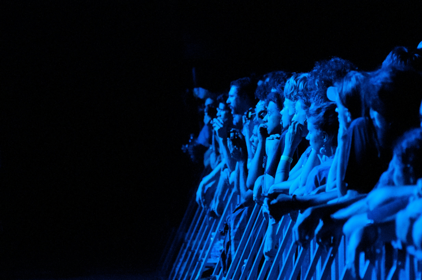 A crowd at a barricade bathed in blue light