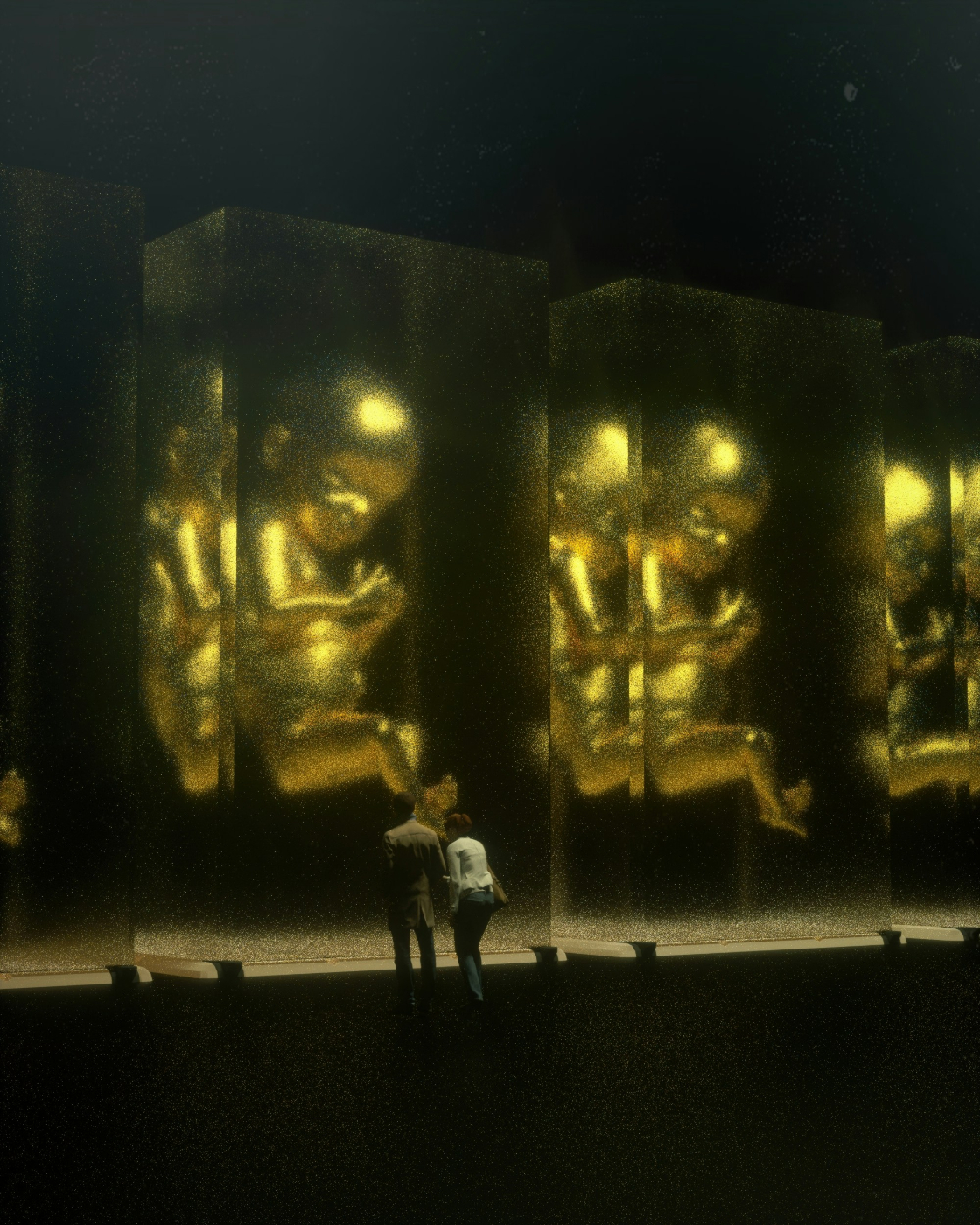 A couple standing in front for an exhibit of giant gold human fetuses in glass casees