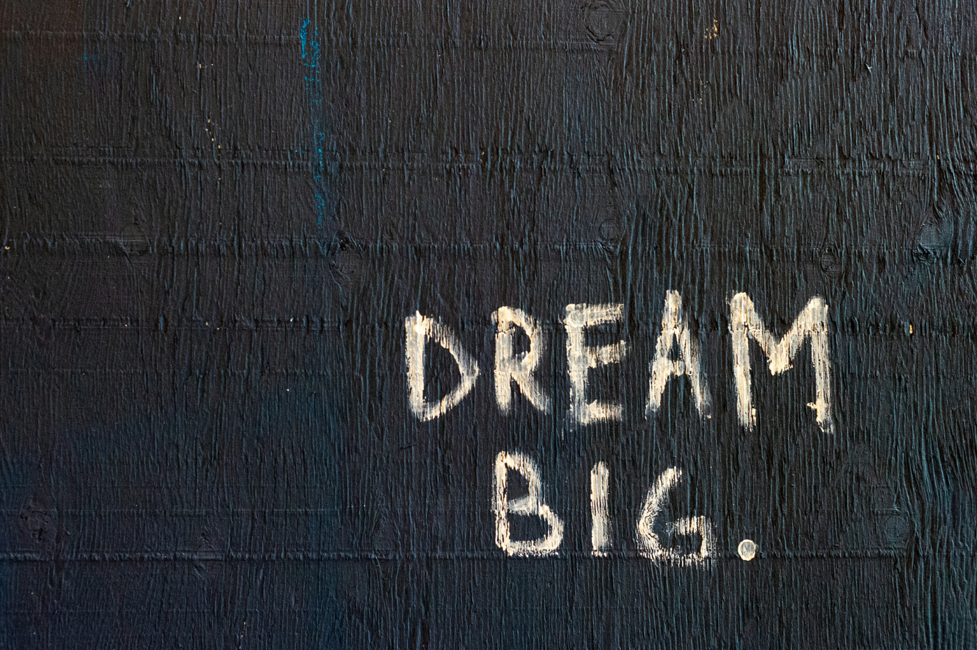 A black wall with Dream Big written on it in white chalk