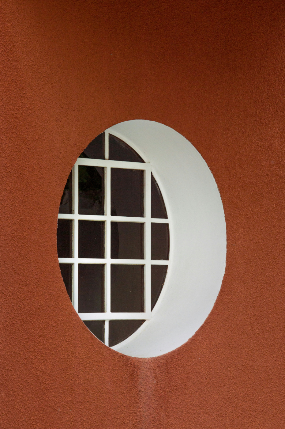A brown wall with a round recessed window with a white border