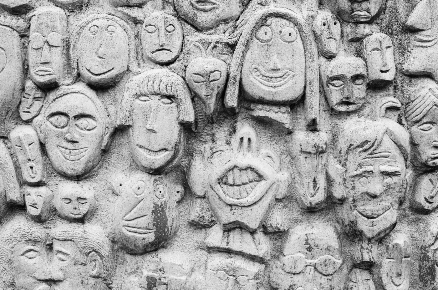 A concrete wall with many cartoon faces carved in it