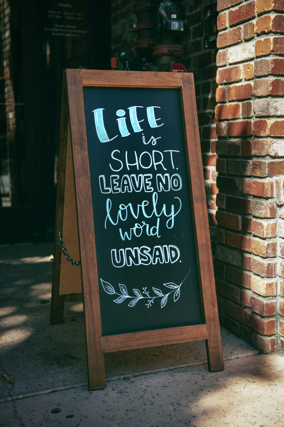 A chalkboard at a restaurant reading: Life is Short Leave no lovely word unsaid
