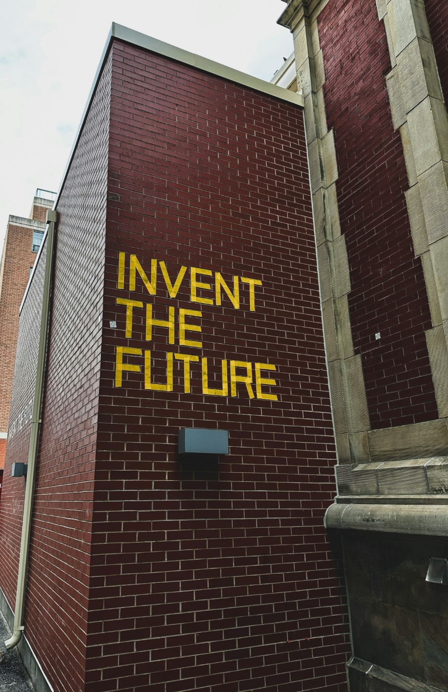 A brick wall with Invent The Future neatly painted on it