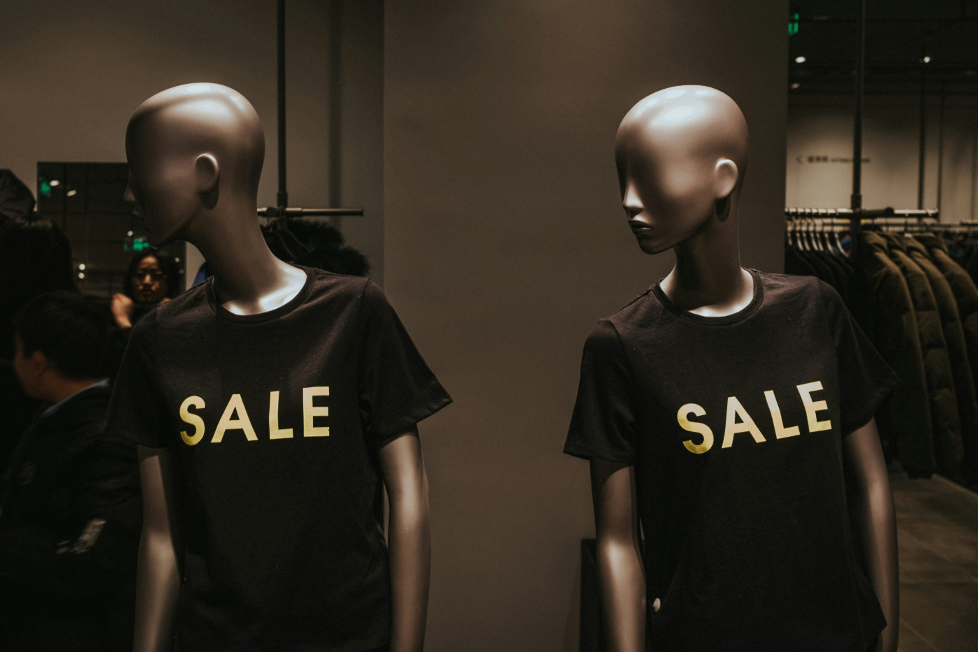 Two mannequins wearing T-shorts that have SALE on them