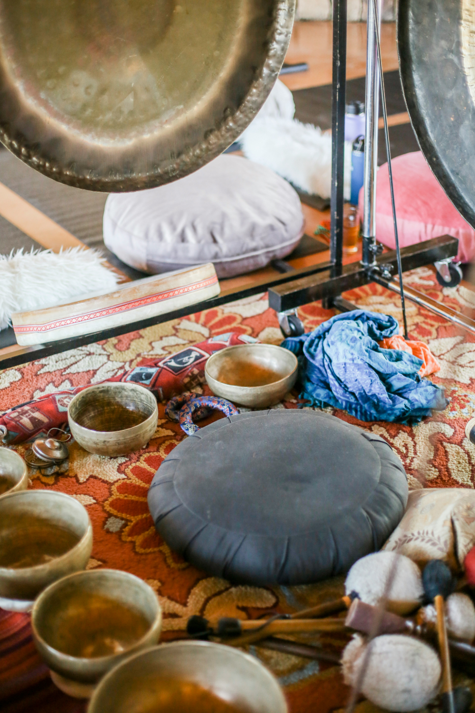 A round pillow surrounded by singing bowls and gongs