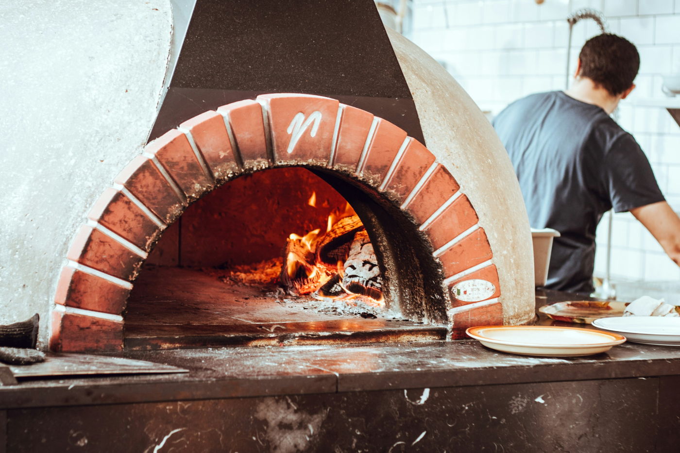 A man working around a brick pizza oven