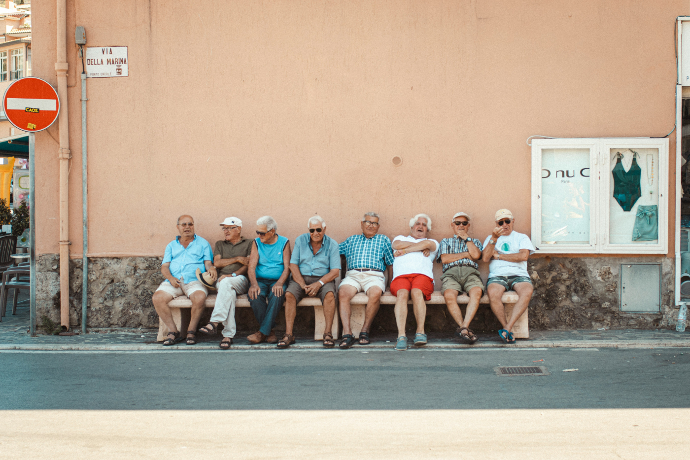 Eight older men sitting on a bench in the Via Della Marina