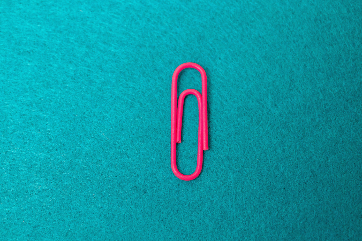 A pink paper clip on a blue background