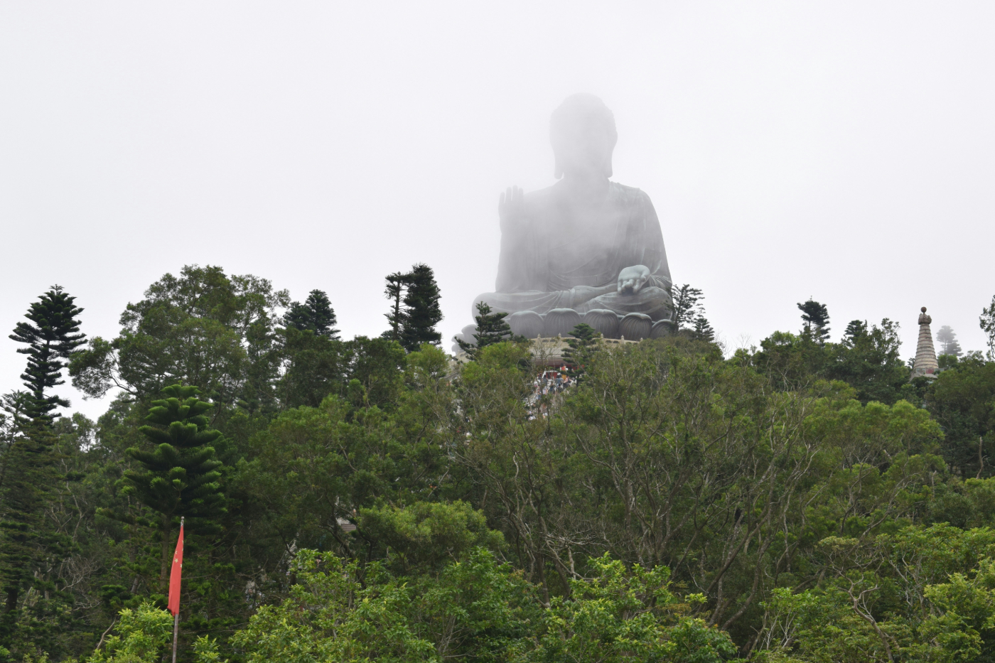 A giant seated Buddha statue in the mist above the trees