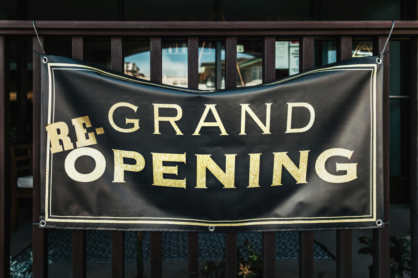 A black banner with gold letters reading: re-grand opening