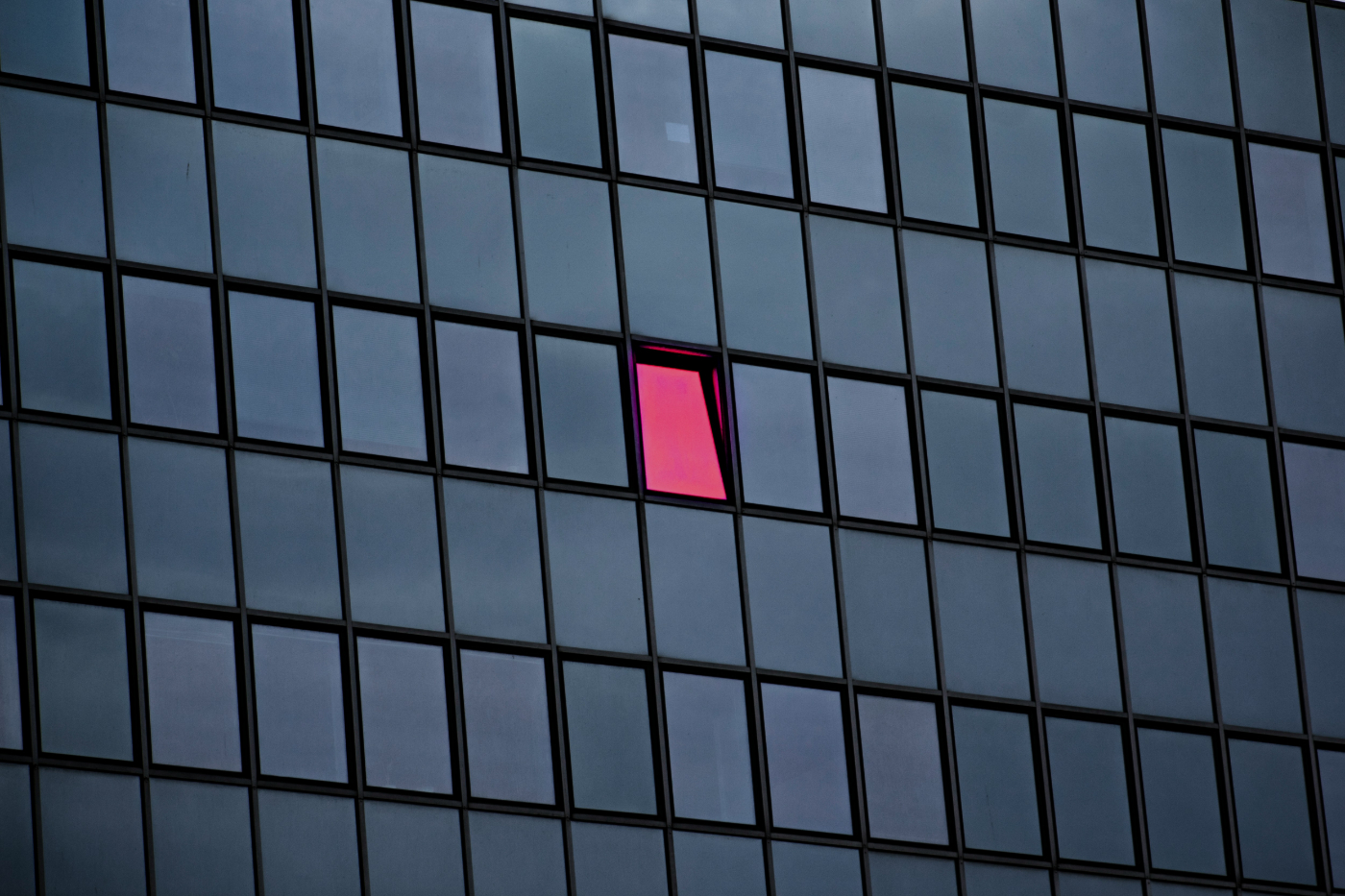 A pink window on a building with grey windows