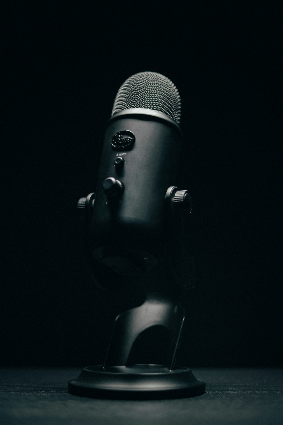 A black microphone on a black table in a dimly lit room
