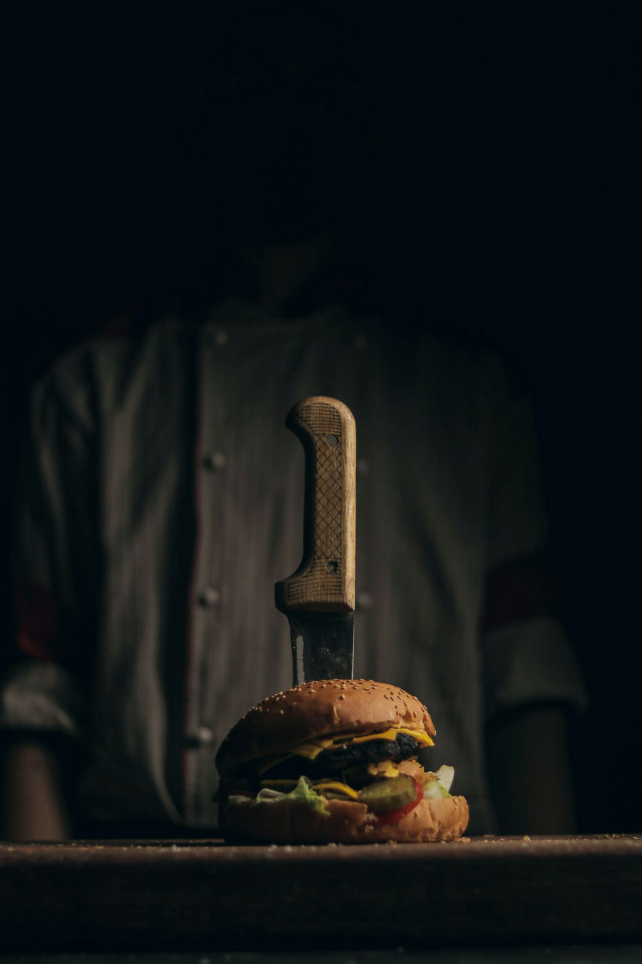 A large burger with a steak knife stuck in it