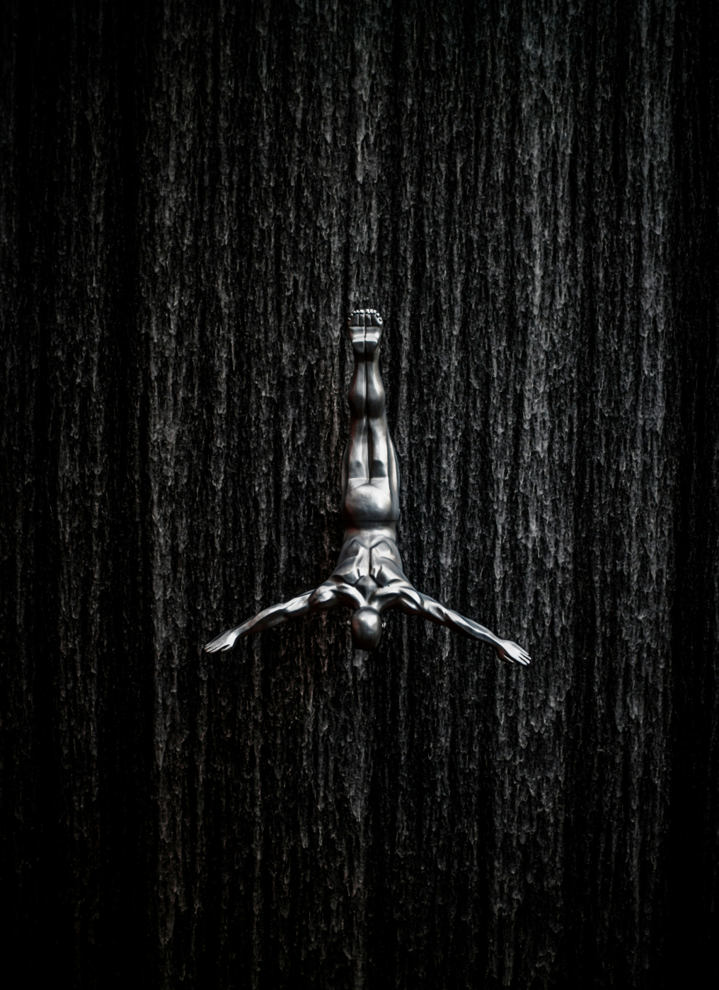 Gray scale of a statue of a man diving in front of a waterfall
