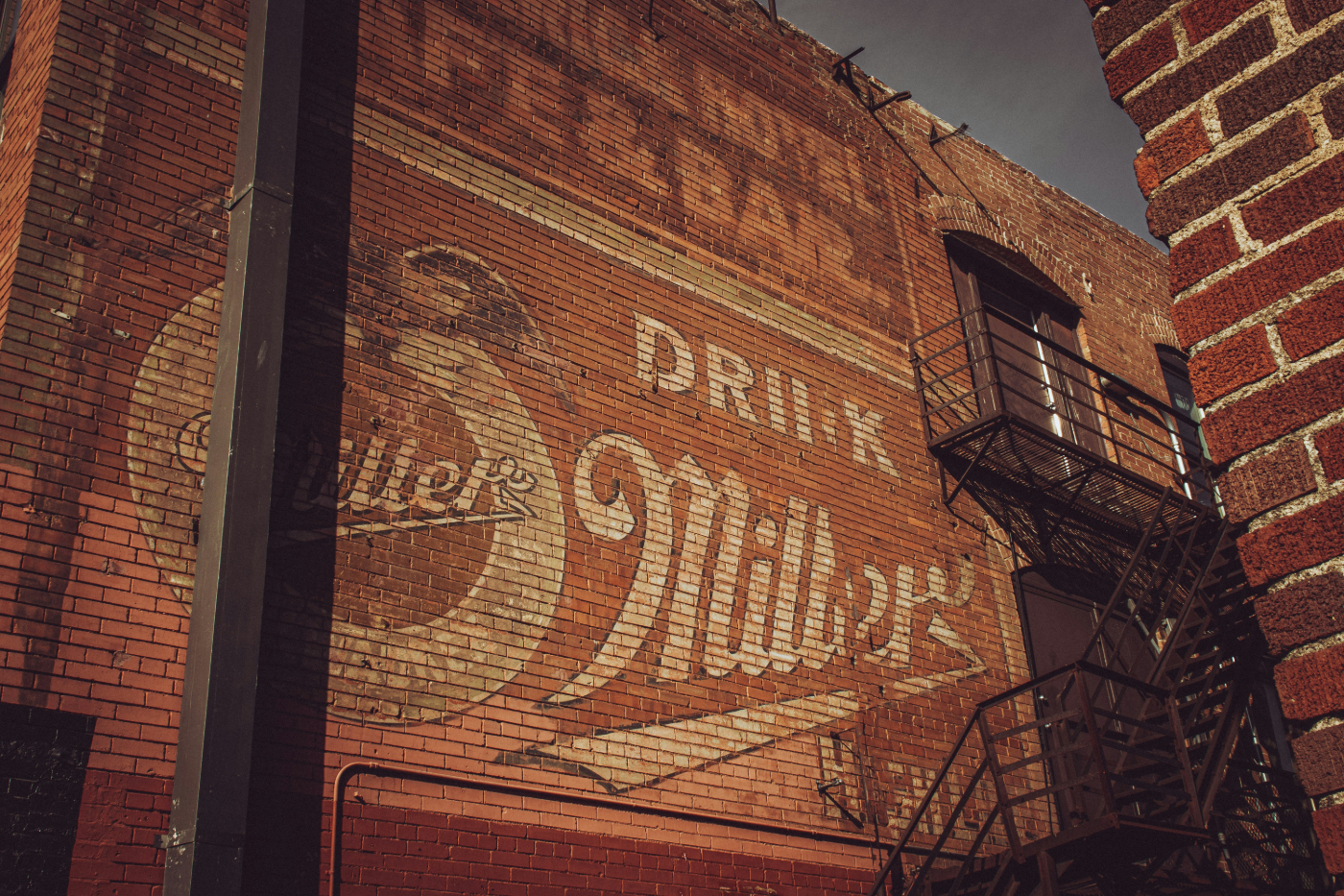 The side of a brick building with a Miller beer and right in the bricks