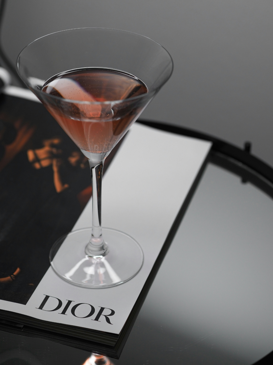 A Cosmo cocktail sitting on a magazine page that reads DIOR