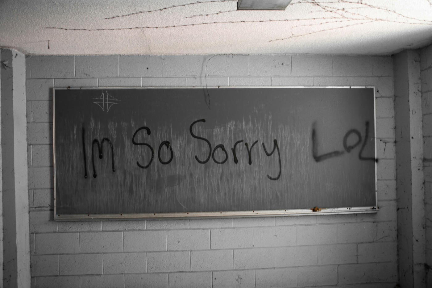 Graffiti on the chalkboard in an abandoned school room reading: I'm So Sorry