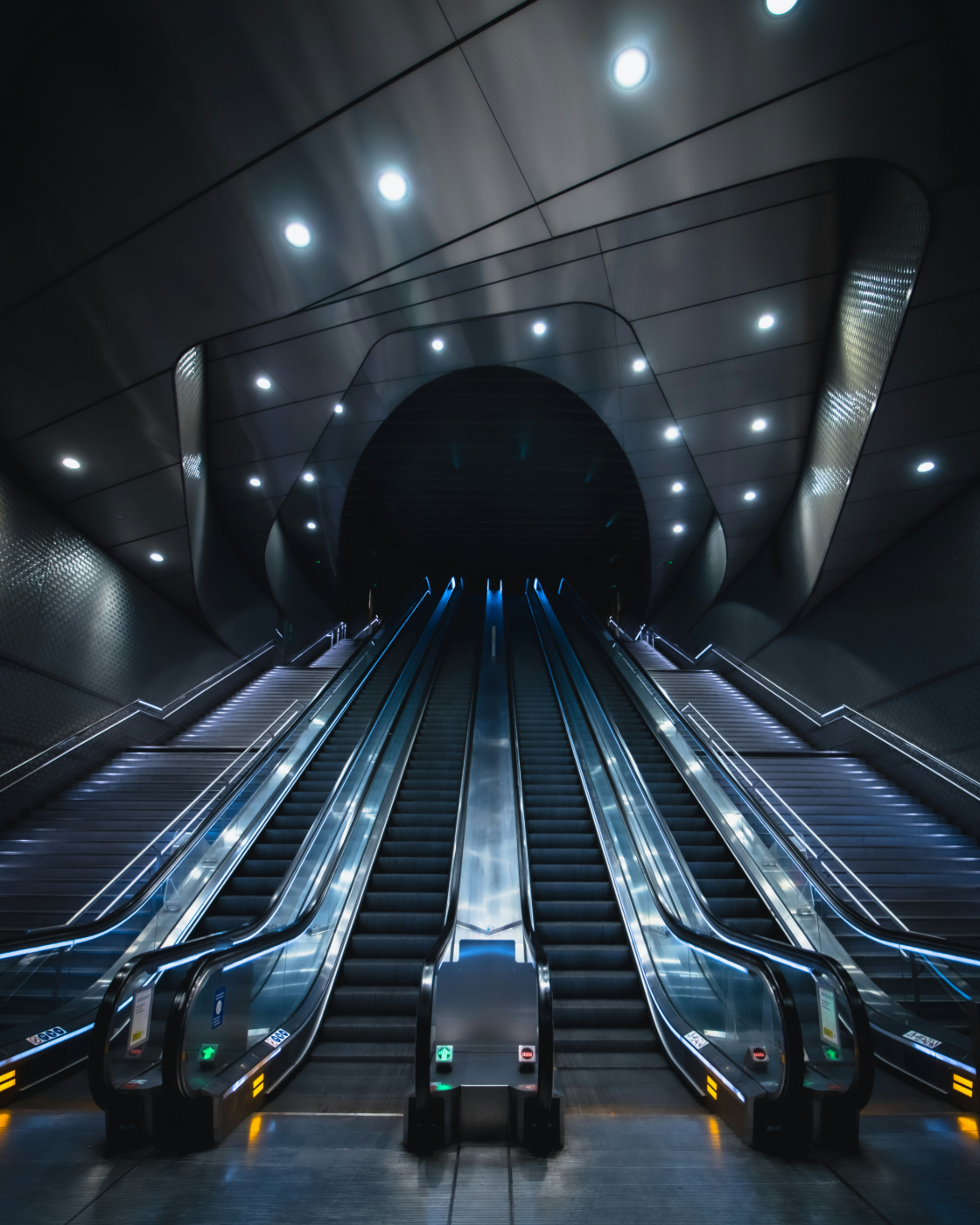 Two flights of stairs and four escalators leading up to a black opening