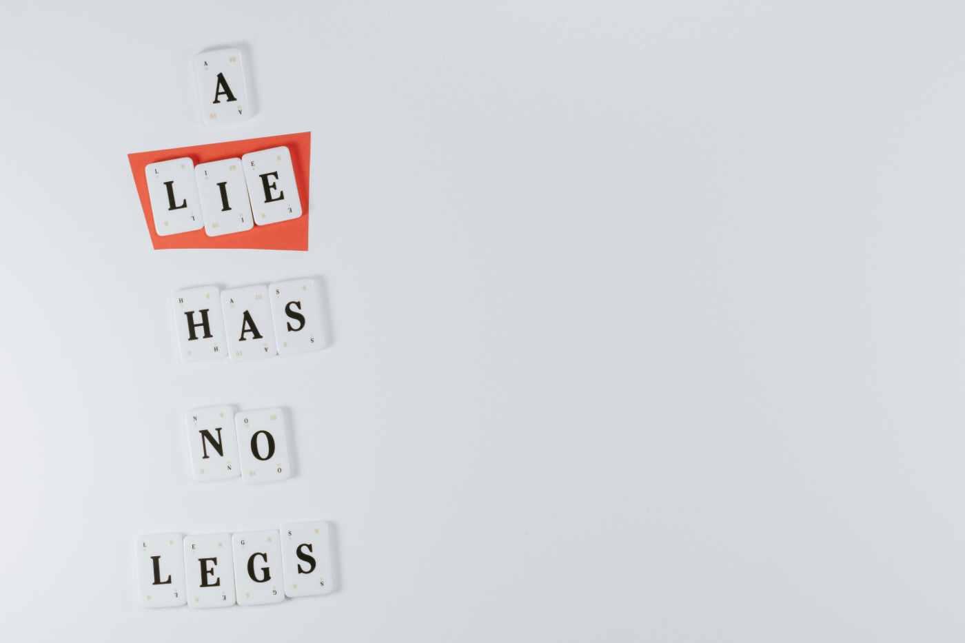 White lettered tiles spelling out A lie Has No Legs, the word lie is on a red background