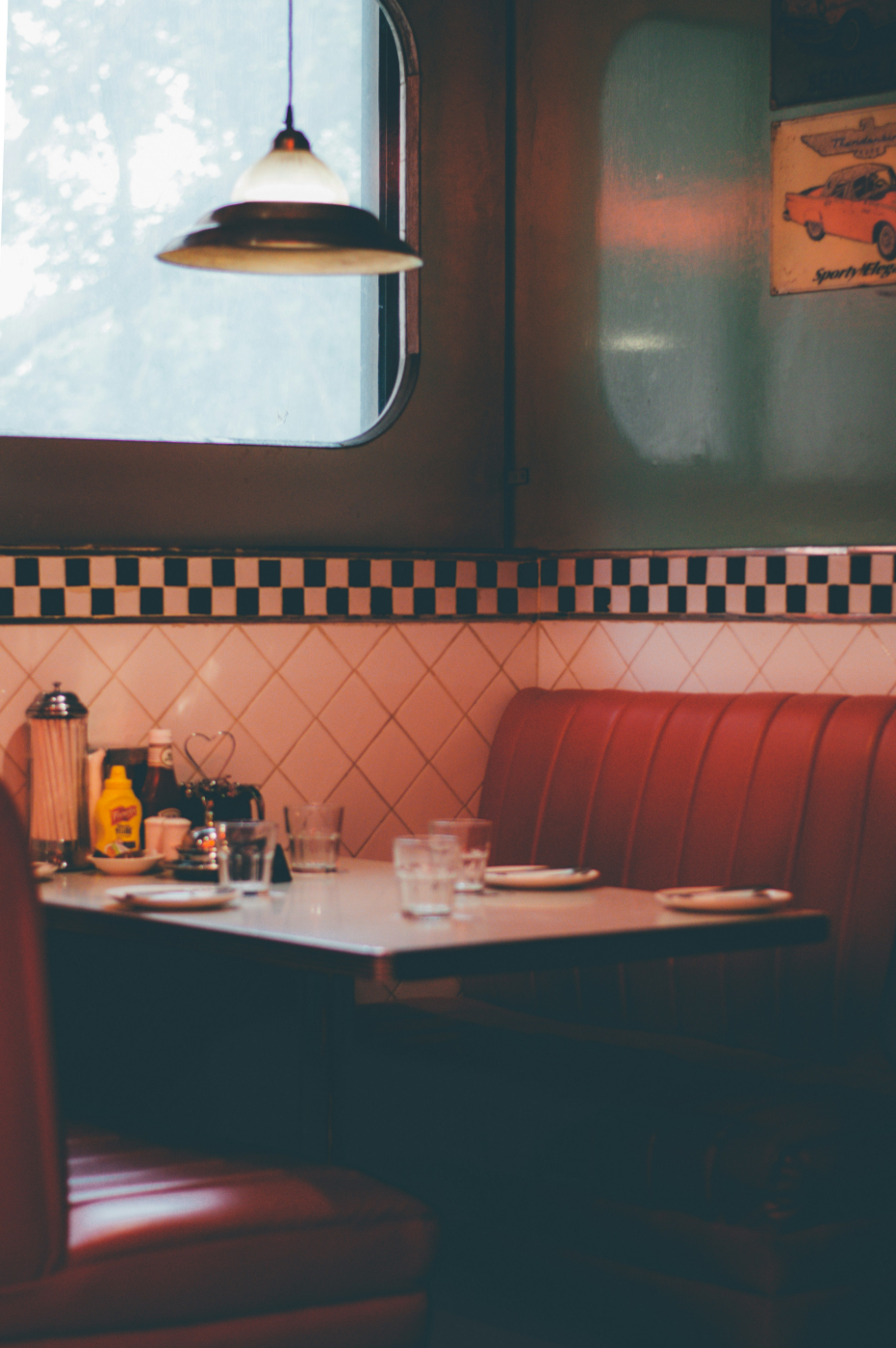 Corner table in a classic diner with red leather bench seats and black and white checked tile