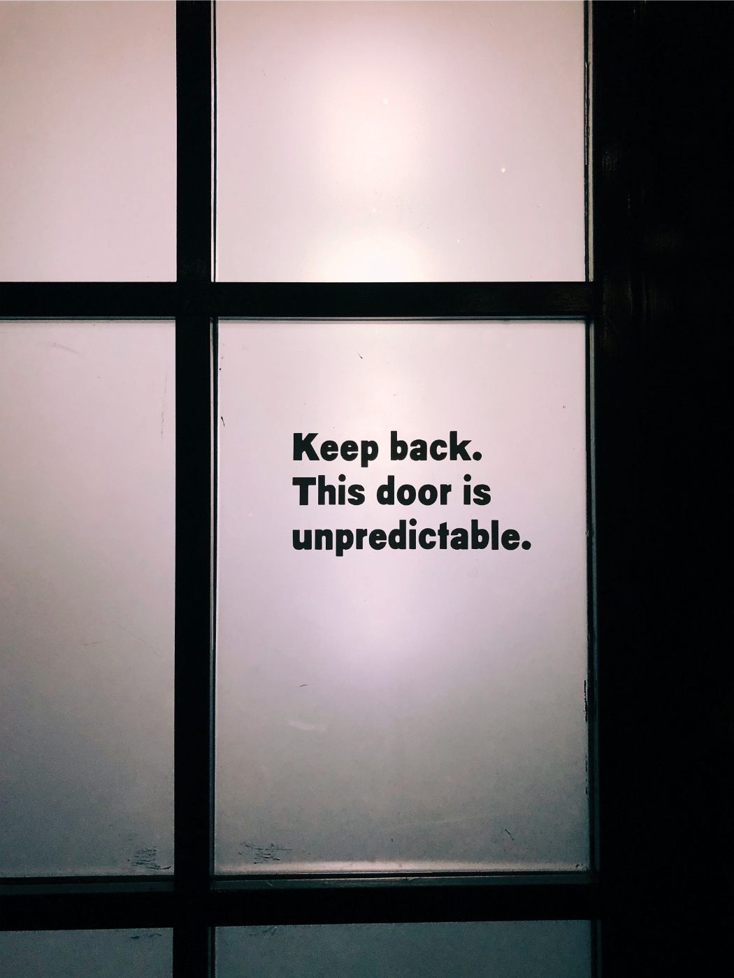 A door with glass panels on one planet is written: Keep Back This Door Is Unpredictable