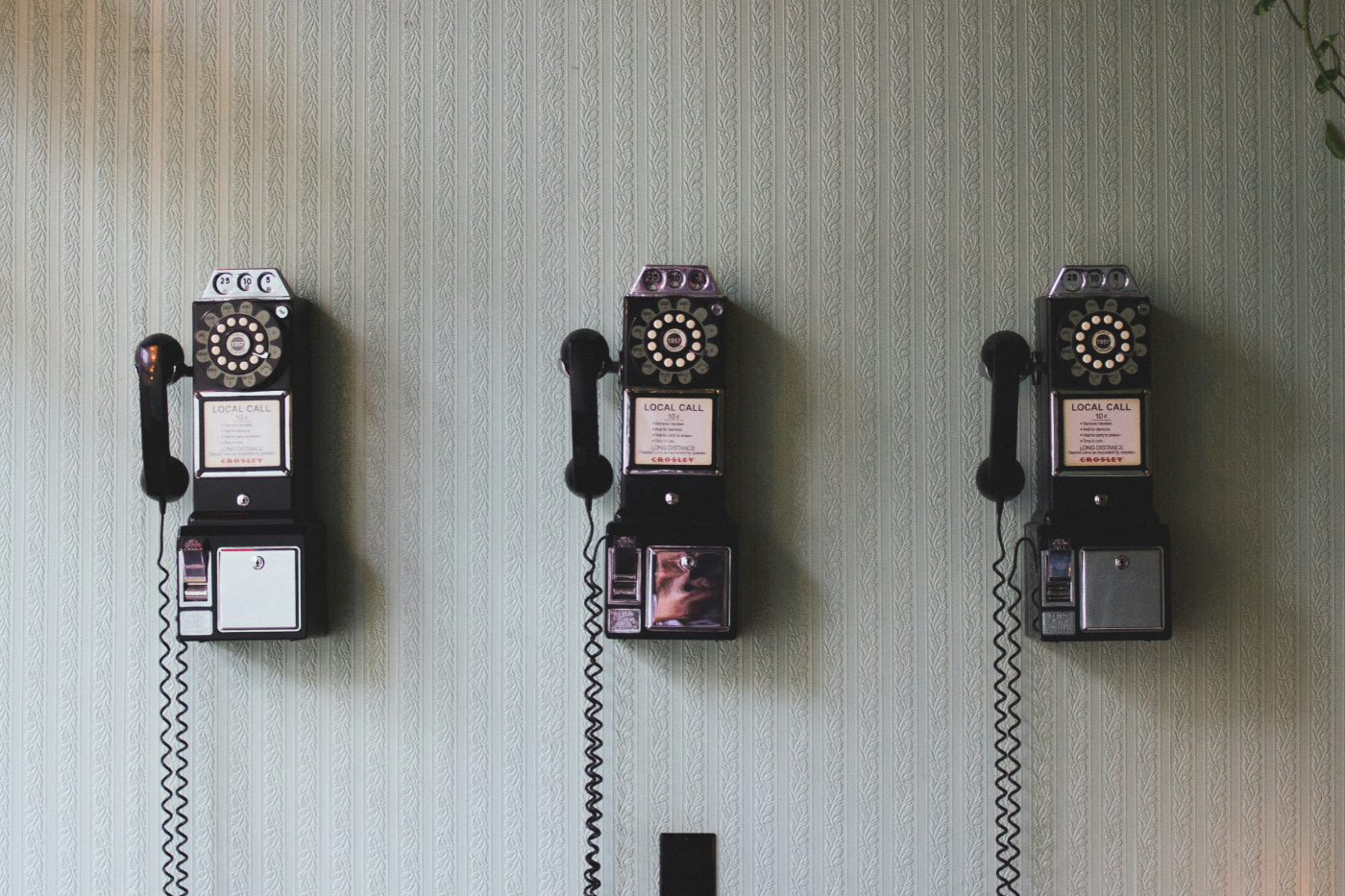 3 old fashioned pay phones on a wall