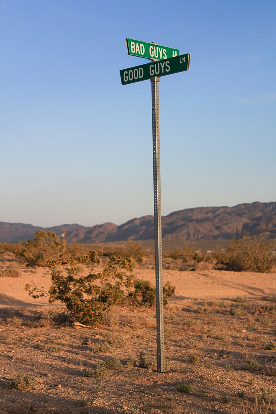 A signpost in the middle of the desert, two street signs: Bad Guy Street & Good Guy Street